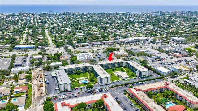 a view of a big yard with large trees and cars parked in front of it