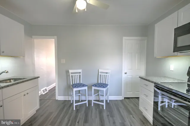 a kitchen with granite countertop white cabinets and stainless steel appliances