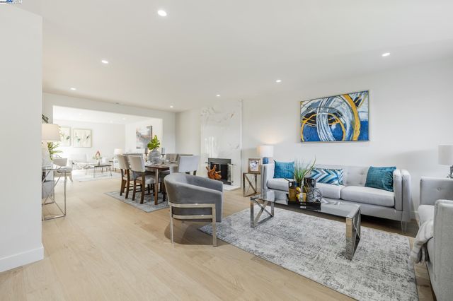 a living room with furniture and a dining table with wooden floor