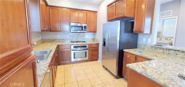 a kitchen with stainless steel appliances granite countertop a refrigerator sink and stove