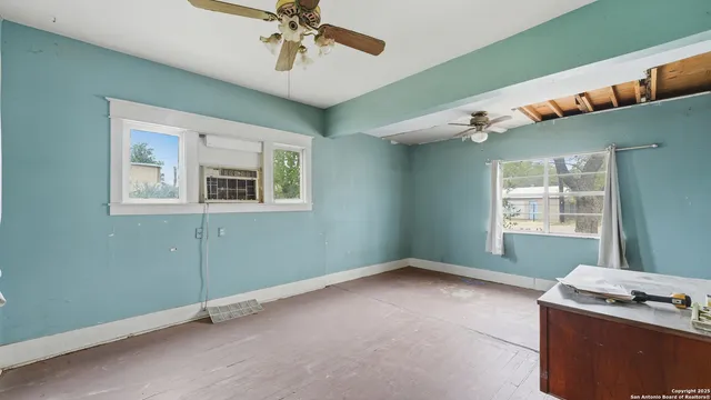 en empty room with windows and ceiling fan
