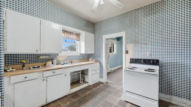 a kitchen with a sink a stove cabinets and a living room