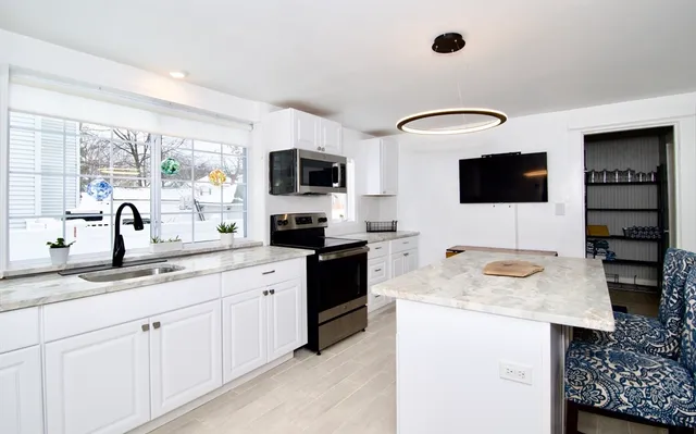 a kitchen with granite countertop a sink and a stove top oven with wooden floor