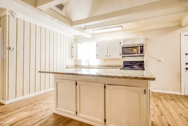 a kitchen with stainless steel appliances granite countertop a stove a sink and a microwave