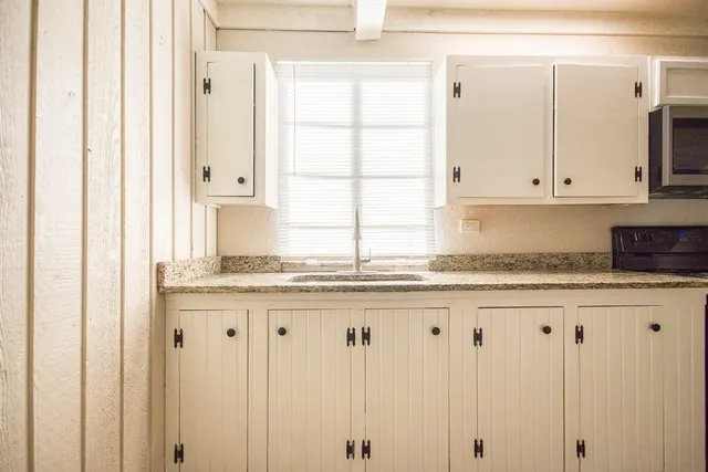 a kitchen with granite countertop white cabinets and sink