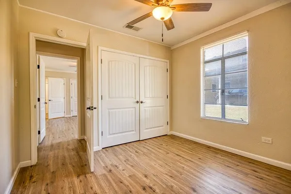 a view of an empty room with wooden floor and a window