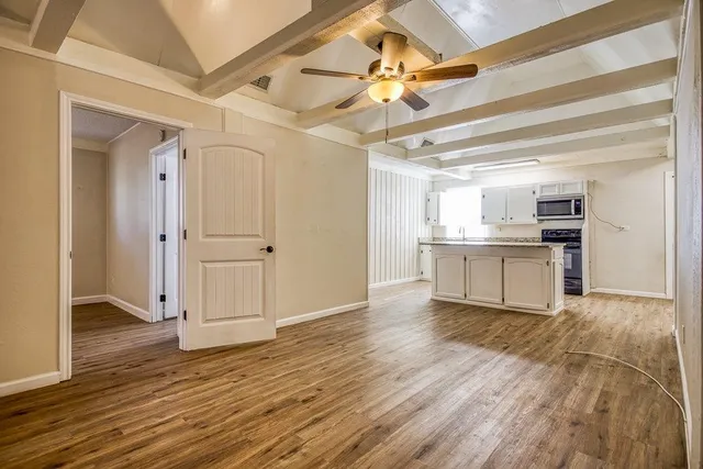 a view of a kitchen with wooden floor a sink and a ceiling fan