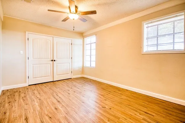 a view of an empty room with wooden floor and a window