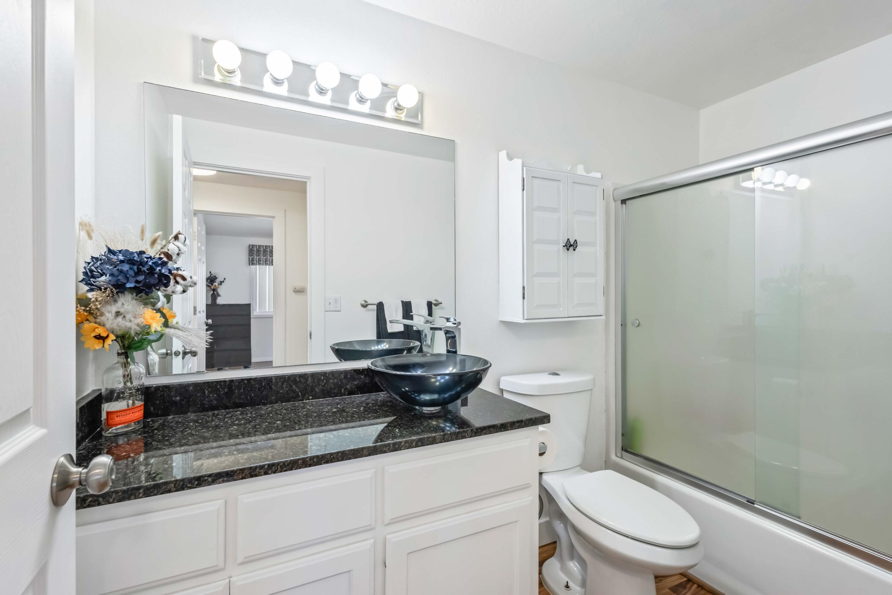 405 East D Street Culver, OR 97734 - Photo 20 of 49 a bathroom with a granite countertop sink a toilet a mirror and shower