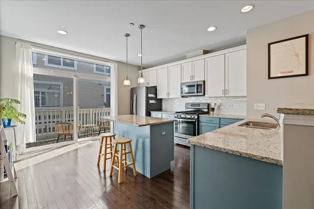 a kitchen with granite countertop a stove a sink a kitchen island with a dining table and wooden floor