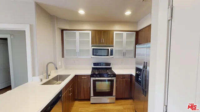 a kitchen with stainless steel appliances a stove a sink and a refrigerator