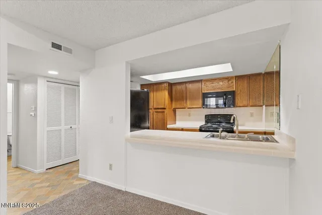 a view of kitchen with stainless steel appliances granite countertop sink and window