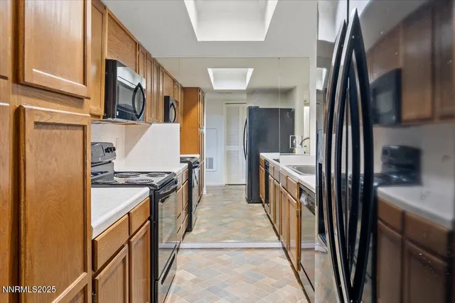a kitchen with stainless steel appliances granite countertop a refrigerator a stove and a sink
