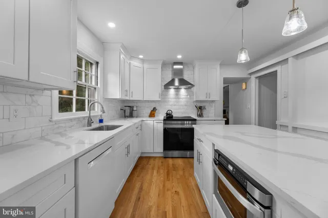 a large kitchen with a center island wooden floor stainless steel appliances and a window