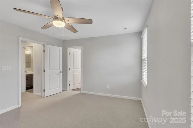 an empty room with a chandelier fan and windows