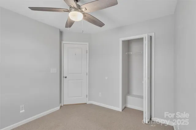 an empty room with closet and a chandelier fan