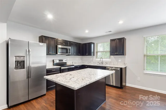 a kitchen with stainless steel appliances granite countertop a refrigerator a sink a stove a microwave and island