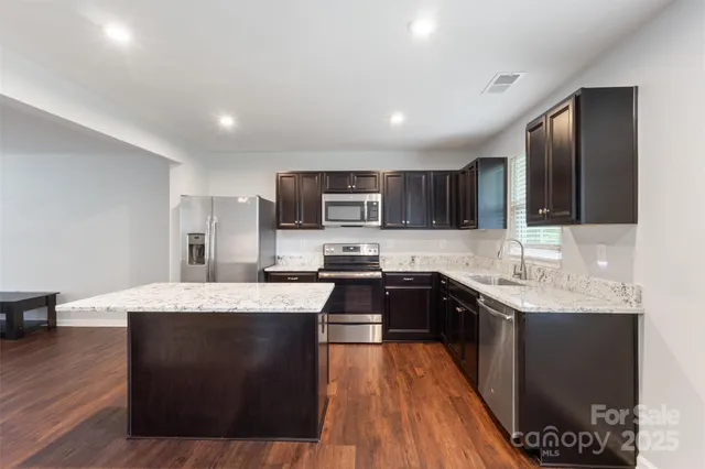 a large kitchen with stainless steel appliances granite countertop a stove a sink dishwasher and a microwave oven with wooden floor