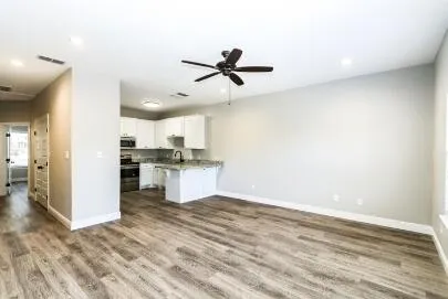 a view of kitchen and empty room with wooden floor