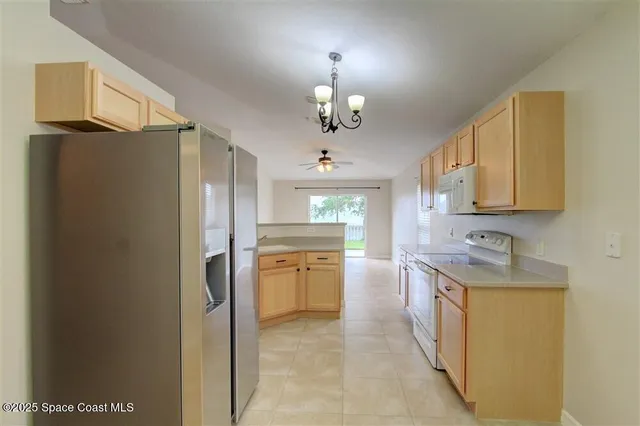 a kitchen with stainless steel appliances granite countertop a refrigerator a sink dishwasher a dining table and chairs with wooden floor