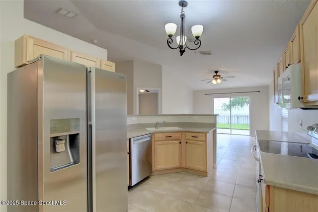a kitchen with stainless steel appliances granite countertop a refrigerator a oven and a view of living room