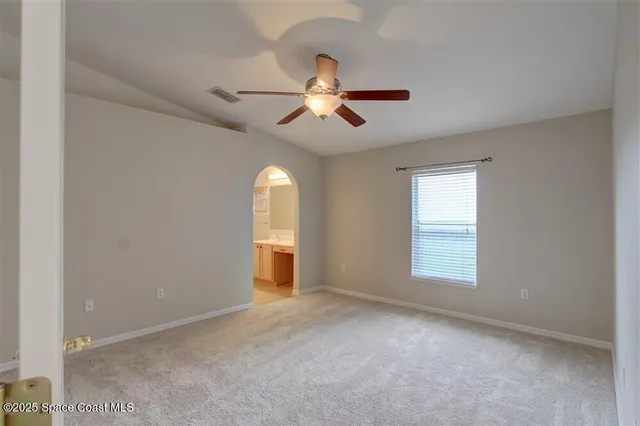 a view of empty room with a ceiling fan and window
