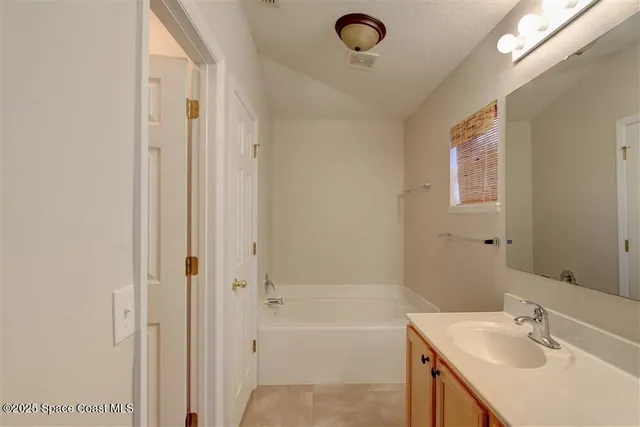 a bathroom with a tub sink vanity granite and shower