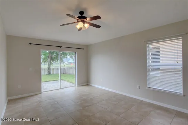 a view of an empty room with chandelier fan and fire place