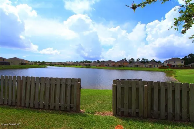 a view of a lake with a big yard and large trees