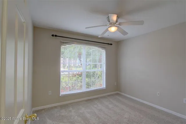 an empty room with a window and a fan