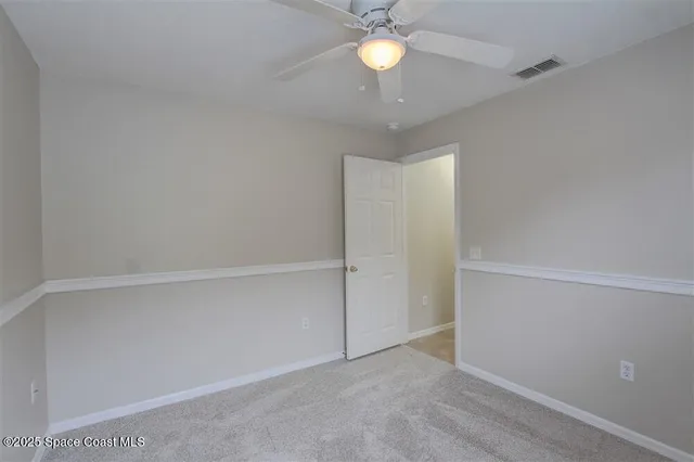 an empty room with a chandelier fan