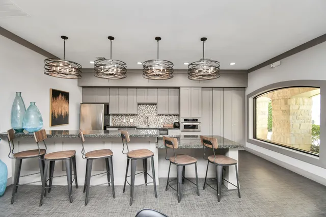 an empty room with a chandelier fan and windows