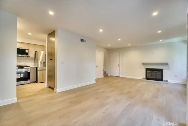 an empty room with kitchen view and a fireplace