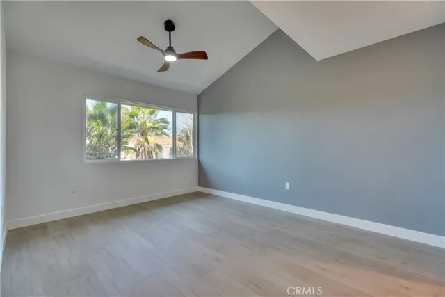an empty room with wooden floor chandelier fan and windows