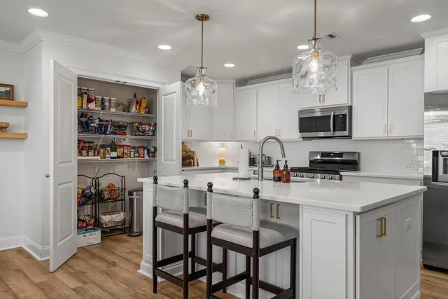 a kitchen with stainless steel appliances granite countertop a stove top oven a sink a dining table and chairs with wooden floor