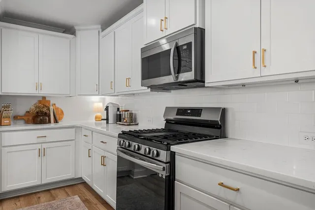 a kitchen with granite countertop white cabinets and stainless steel appliances