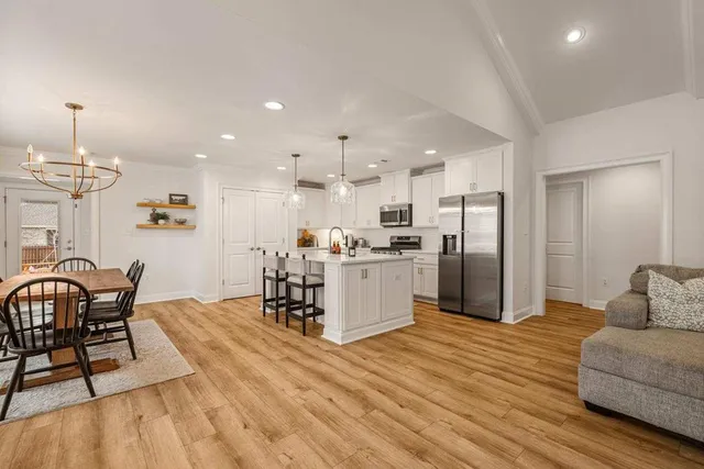 a kitchen with stainless steel appliances kitchen island granite countertop a refrigerator a stove a kitchen island with a dining table and chairs