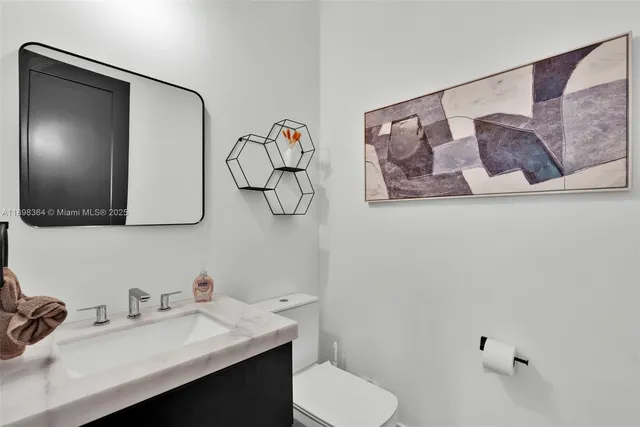 a bathroom with a sink vanity mirror and toilet