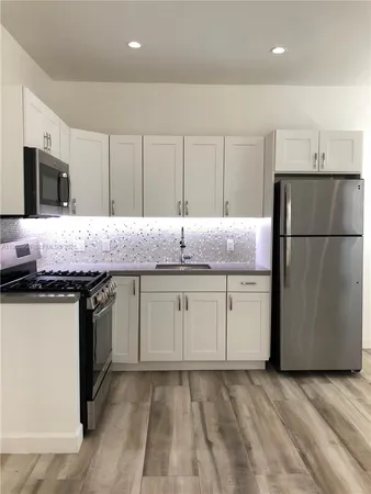 a kitchen with granite countertop cabinets stainless steel appliances and wooden floor