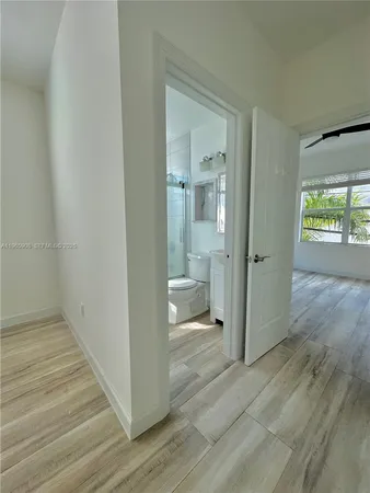 a view of a hallway with wooden floor and a bathroom