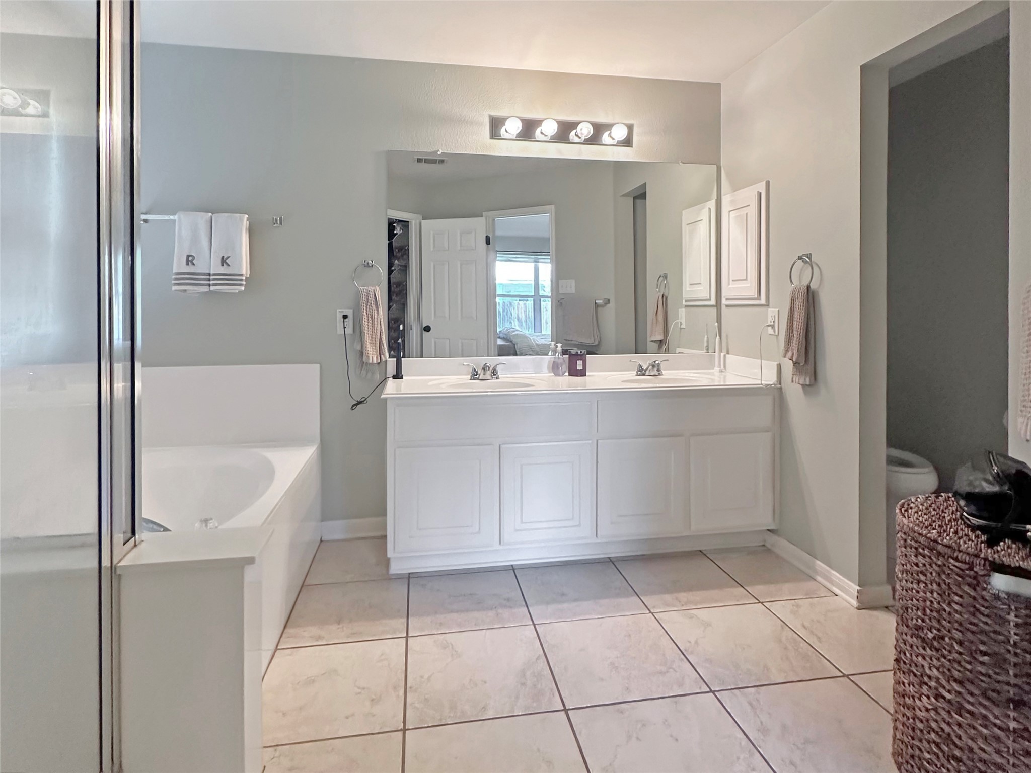 20213 Kearney Hill Road Pflugerville, TX 78660 - Photo 17 of 27 Dual vanities and a deep soaking tub create a luxurious primary bathroom oasis.