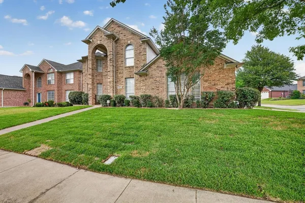 a view of a brick building next to a yard with big trees