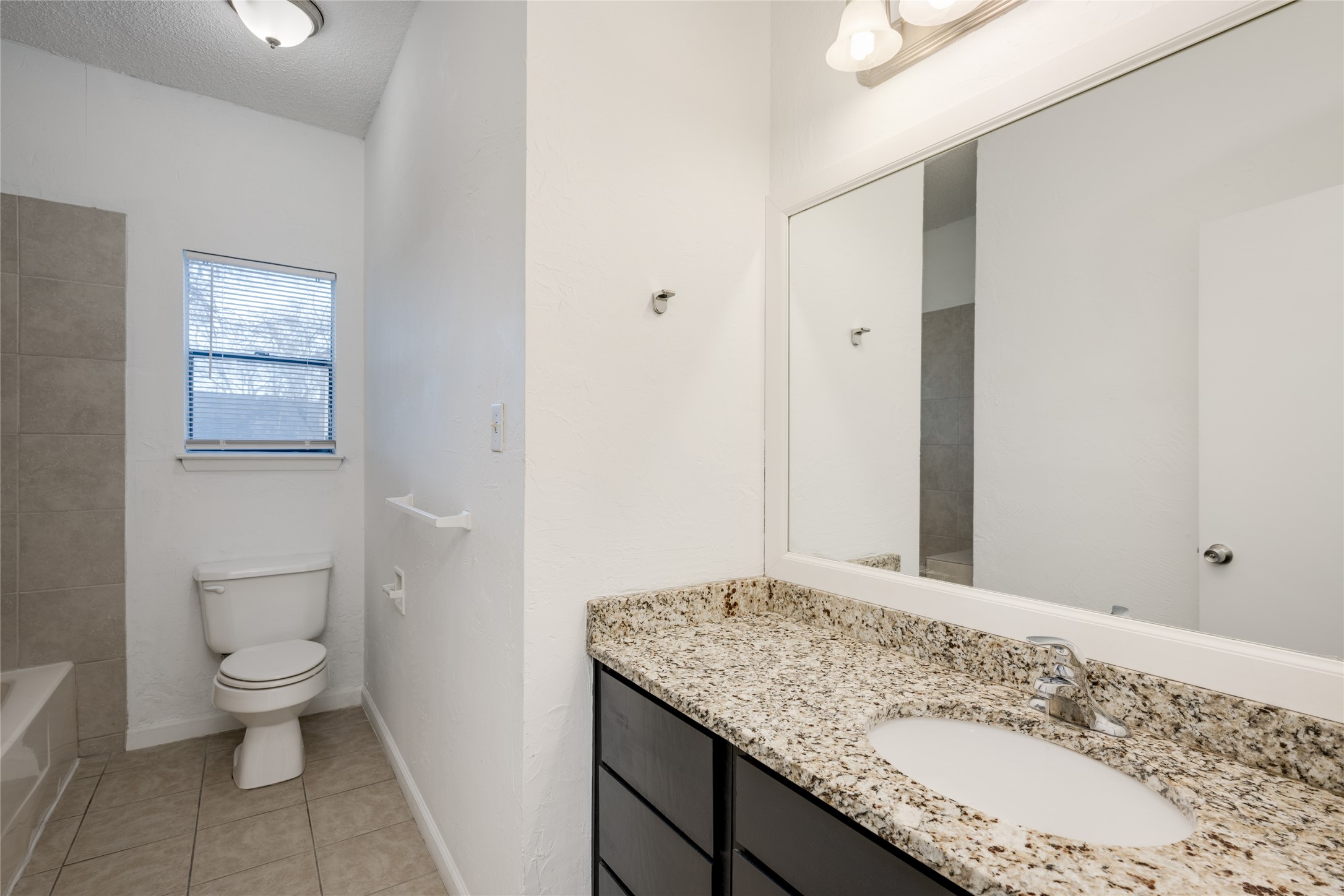 5304 Indio Cove, Unit B Austin, TX 78745 - Photo 20 of 40 a bathroom with a granite countertop sink a toilet and a mirror