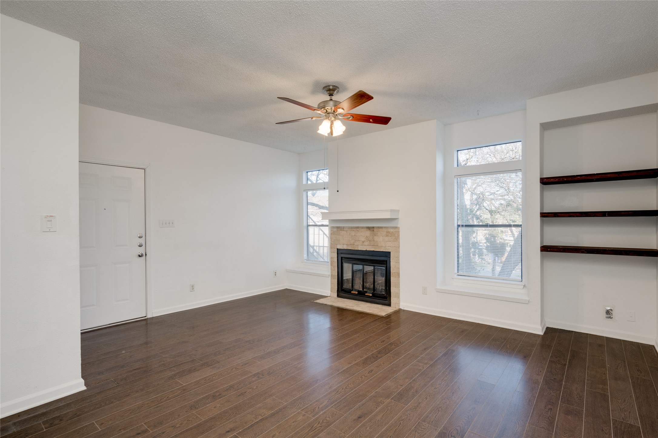 5304 Indio Cove, Unit B Austin, TX 78745 - Photo 5 of 40 an empty room with wooden floor a chandelier fan and a fireplace
