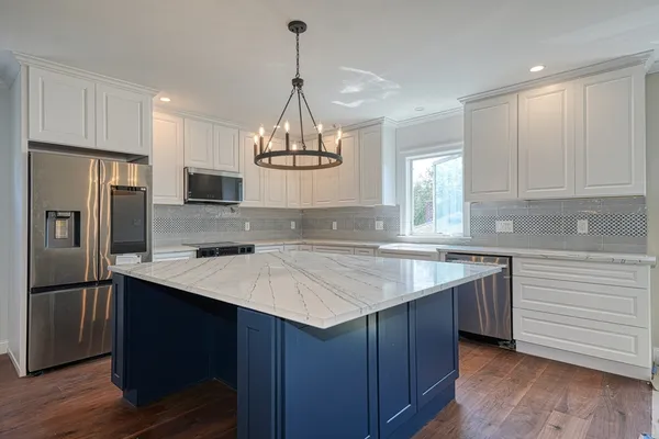 a kitchen with a sink a center island cabinets and stainless steel appliances