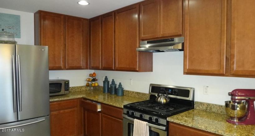 11026 West Elm Street Phoenix, AZ 85037 - Photo 6 of 20 a kitchen with granite countertop wooden cabinets and a stove top oven