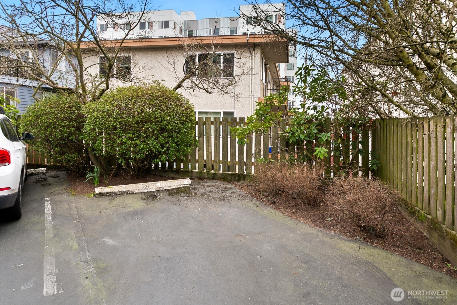 2031 Northwest 59th Street, Unit 101 Seattle, WA 98107 - Photo 22 of 22 a view of a white house with large trees and plants