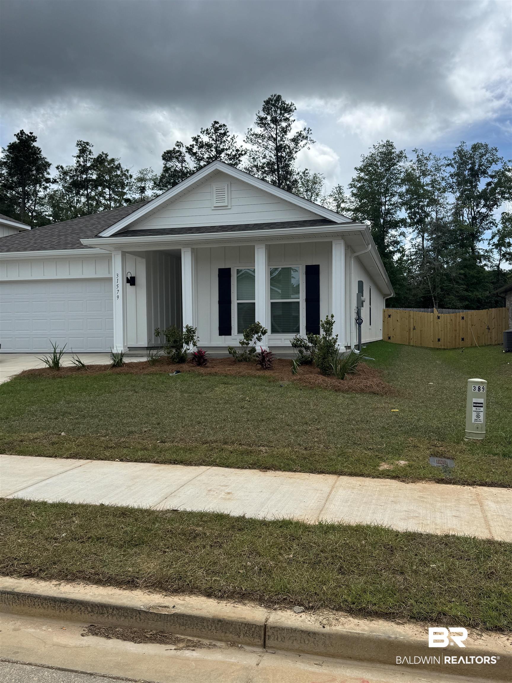 31579 Lyon Road Daphne, AL 36527 - Photo 1 of 47 White board and batten exterior with dark shutters, an attached garage, and a covered porch entry