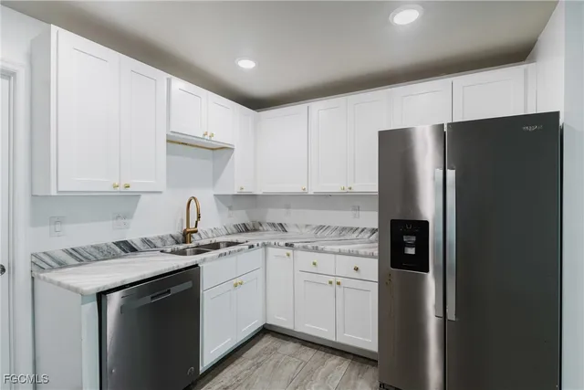 a kitchen with a sink a refrigerator and white cabinets