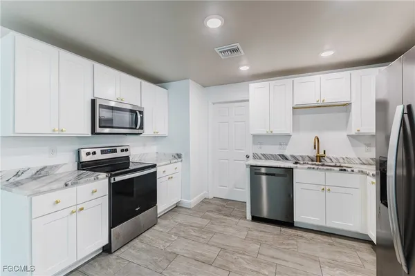 a kitchen with stainless steel appliances granite countertop a stove top oven a sink dishwasher a refrigerator and a microwave